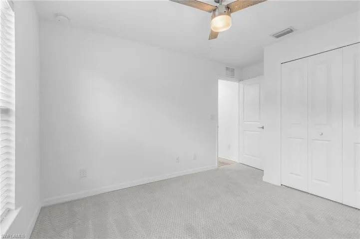 Unfurnished bedroom featuring light colored carpet, a closet, and ceiling fan