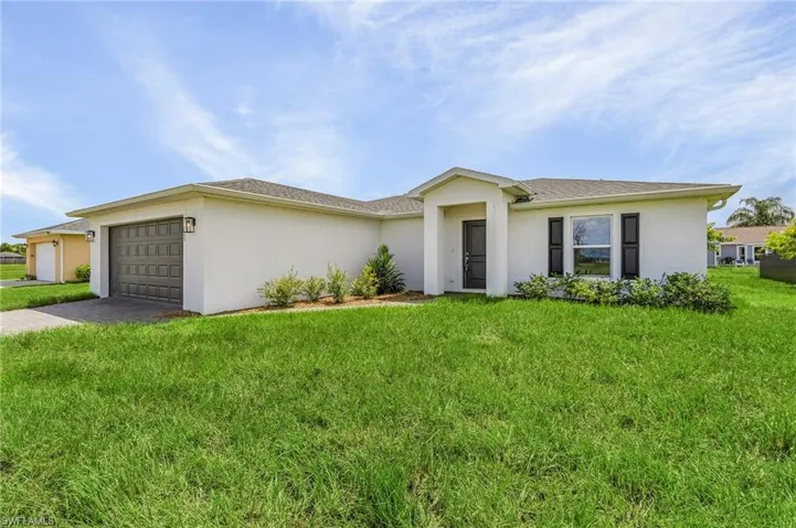 Ranch-style house featuring a garage and a front lawn