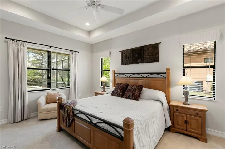Bedroom with light colored carpet, a ceiling fan, a raised ceiling, and recessed lighting