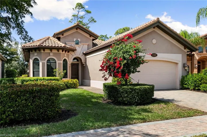 Mediterranean / spanish house with stucco siding, an attached garage, driveway, and a front yard