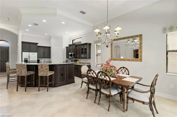 Dining space featuring arched walkways, hanging lights, and ornamental molding