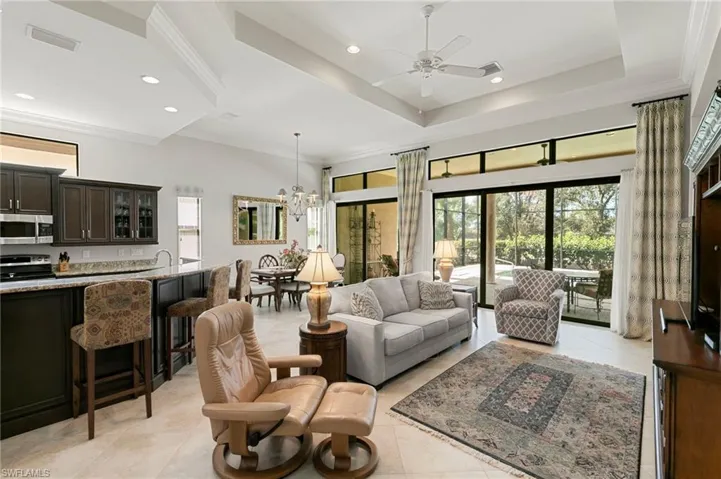 Living room featuring ornamental molding, suspended lighting, ceiling fan, light tile patterned floors, and a high ceiling