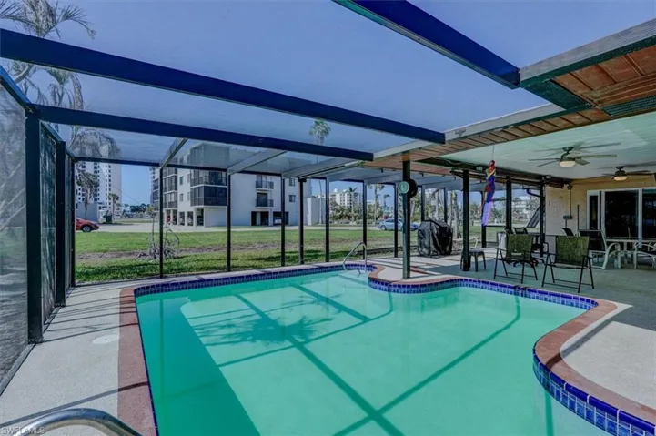 View of swimming pool with a lanai, a grill, ceiling fan, and a patio area