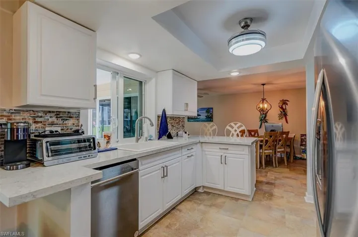 Kitchen featuring stainless steel appliances, sink, white cabinets, and kitchen peninsula