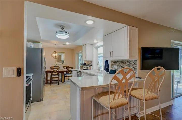 Kitchen with white cabinetry, a breakfast bar, appliances with stainless steel finishes, and kitchen peninsula