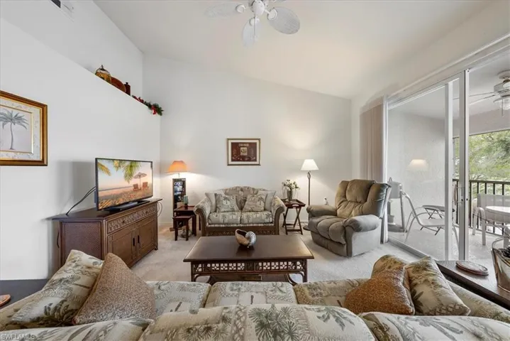 Living room featuring ceiling fan, vaulted ceiling, and light colored carpet
