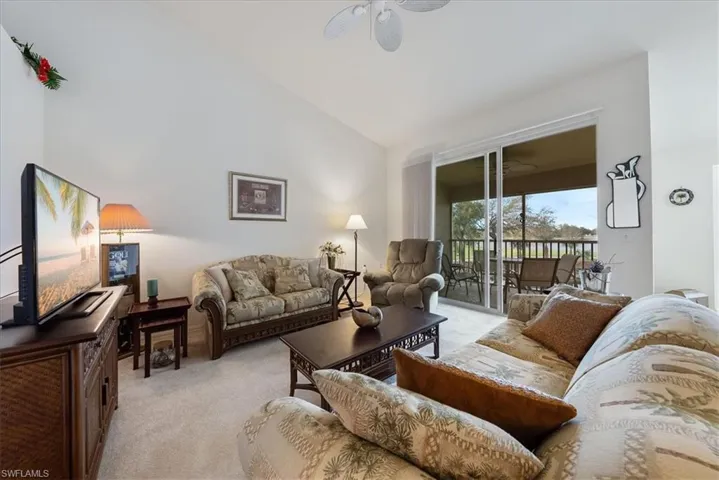Living area featuring a ceiling fan, light colored carpet, and high vaulted ceiling
