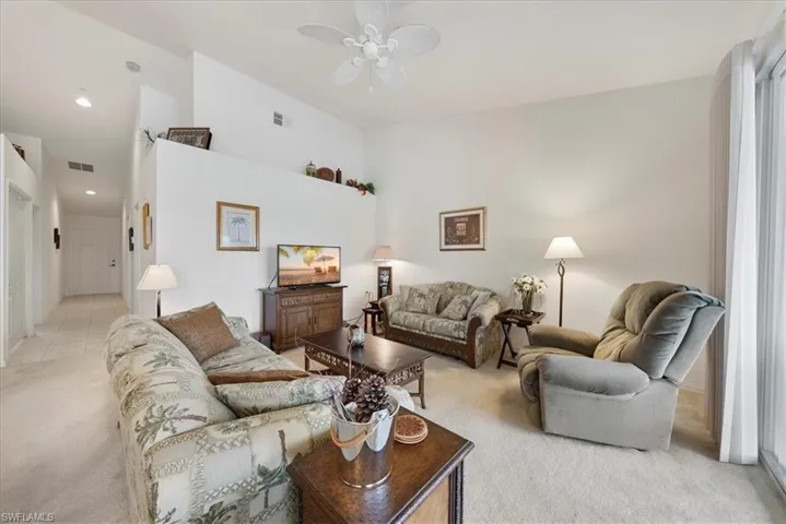 Living room with recessed lighting, light carpet, a ceiling fan, a towering ceiling, and visible vents