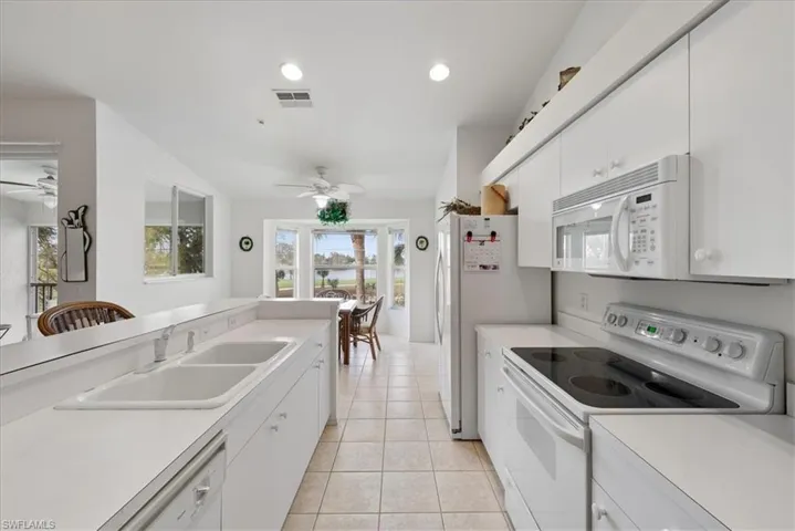 Kitchen featuring white appliances, ceiling fan, light countertops, and a sink