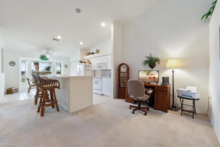 Office area featuring light carpet, light tile patterned floors, visible vents, high vaulted ceiling, and recessed lighting