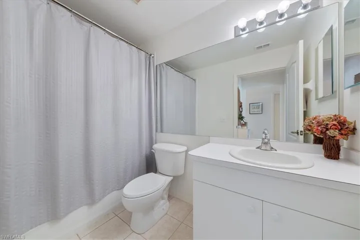 Full bathroom with toilet, tile patterned flooring, visible vents, and vanity