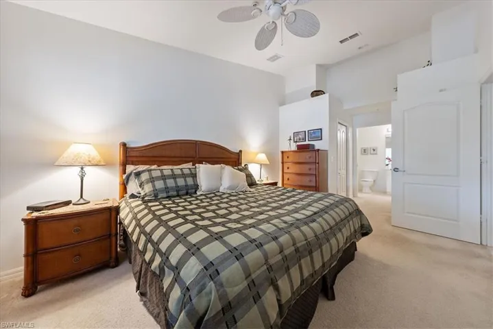 Bedroom with light carpet, a ceiling fan, visible vents, and connected bathroom