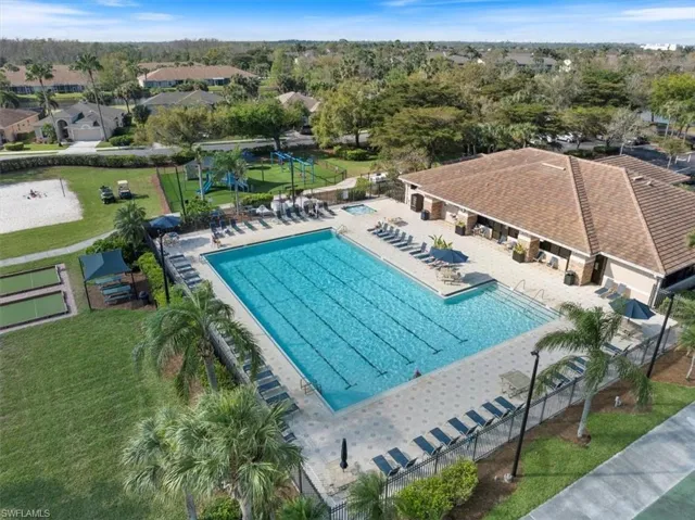 Community pool featuring a patio area, fence, and a lawn