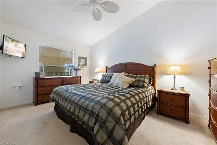 Bedroom featuring lofted ceiling, light carpet, a ceiling fan, and baseboards