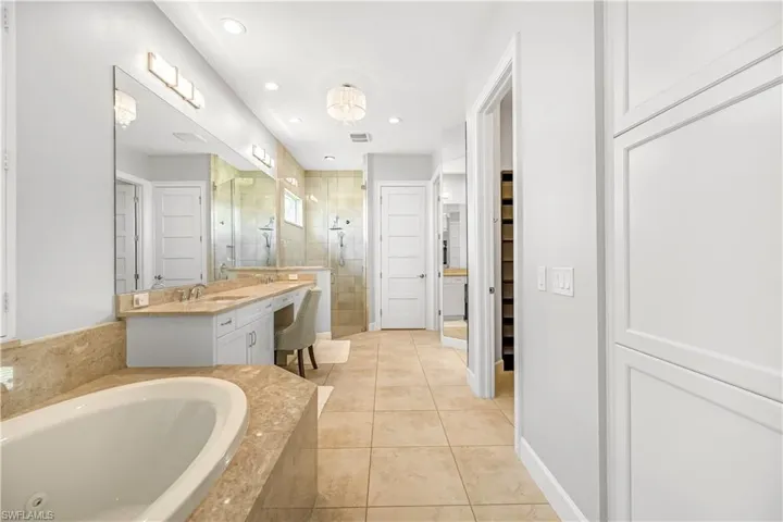 Full bathroom featuring a closet, vanity, a stall shower, a jetted tub, and recessed lighting