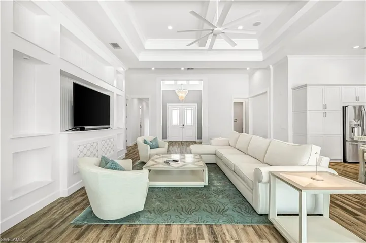 Living area with wood finished floors, crown molding, a high ceiling, recessed lighting, and ceiling fan