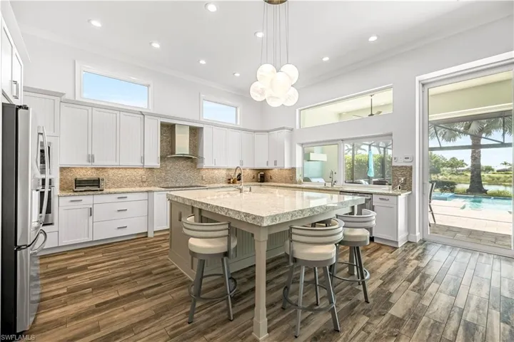 Kitchen featuring tasteful backsplash, pendant lighting, appliances with stainless steel finishes, a kitchen breakfast bar, and light stone countertops