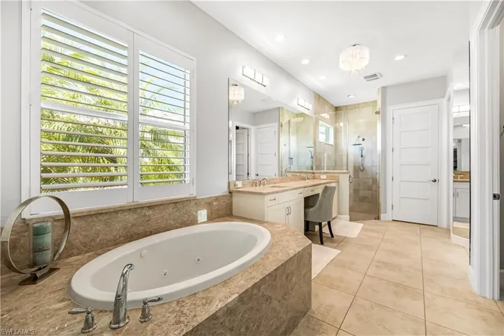 Bathroom featuring a shower stall, a jetted tub, vanity, light tile patterned floors, and recessed lighting