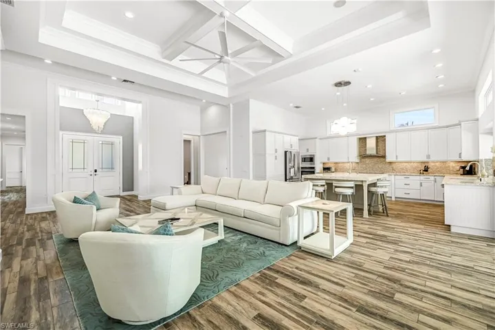 Living room with recessed lighting, coffered ceiling, a ceiling fan, crown molding, and beamed ceiling
