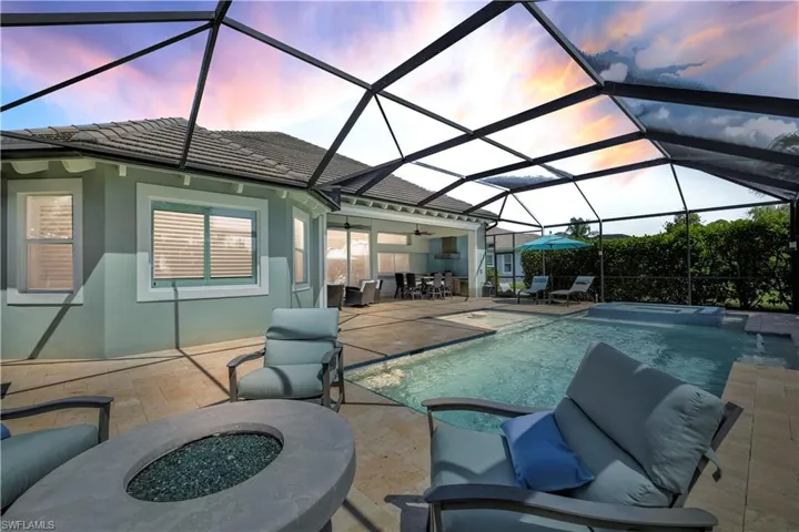 View of swimming pool with a patio, a sunroom, an outdoor living space with a fire pit, a pool with connected hot tub, and a lanai