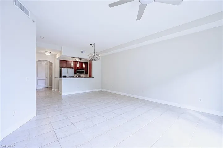 Unfurnished living room with ceiling fan with notable chandelier and light tile patterned floors