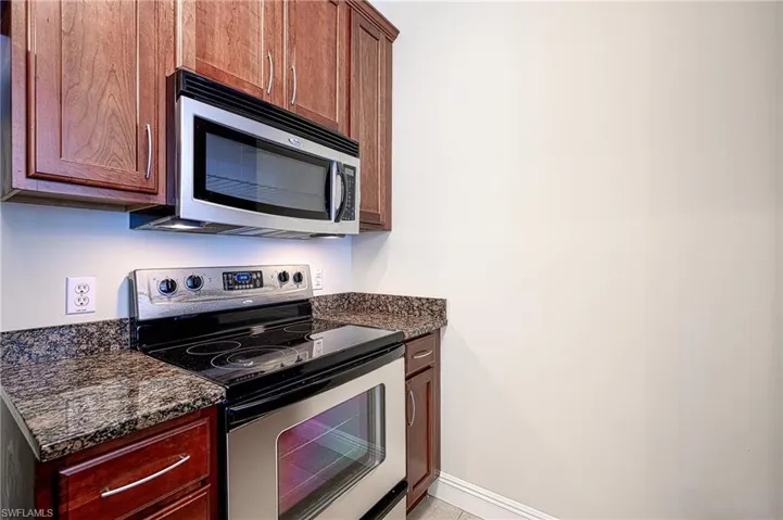 Kitchen with appliances with stainless steel finishes and dark stone counters