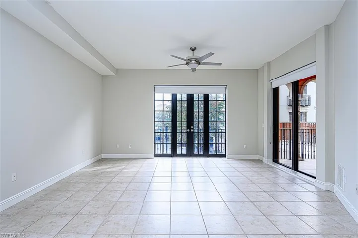 Empty room featuring ceiling fan, light tile patterned floors, and french doors