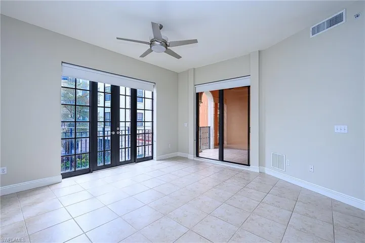 Tiled spare room featuring ceiling fan and french doors