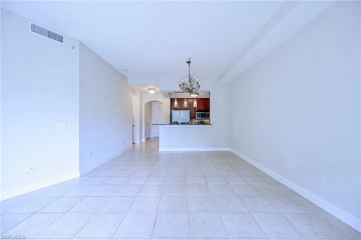 Unfurnished living room with a chandelier and light tile patterned floors