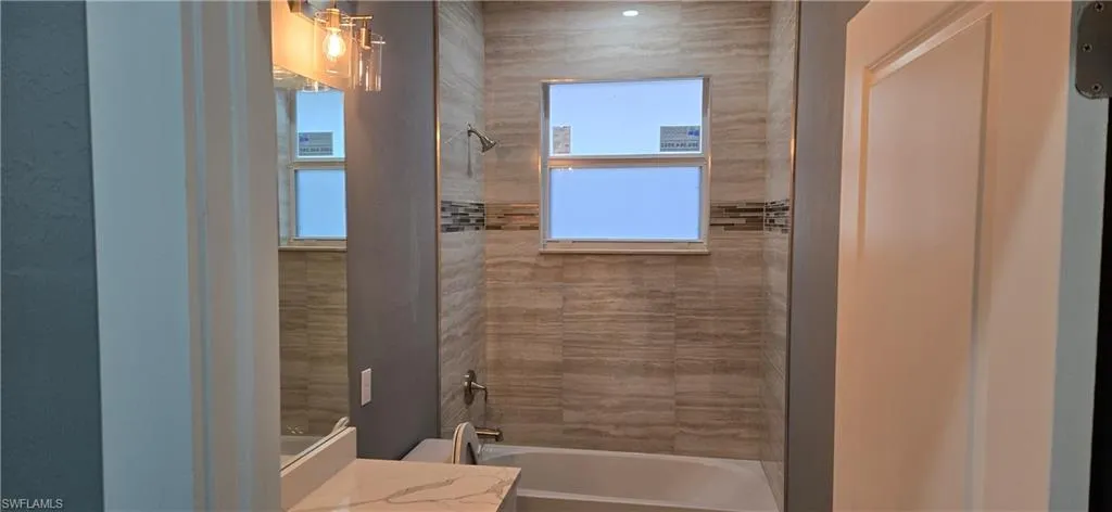 Full bath featuring tub / shower combination, vanity, and plenty of natural light