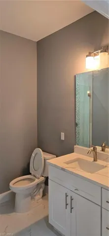Full bath featuring toilet, a walk in shower, marble finish flooring, and vanity