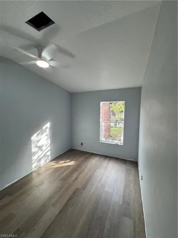 Room featuring wood-finish flooring, a window, and a ceiling fan with integrated lighting
