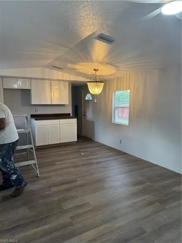 Open-concept living space featuring wood-finish flooring, a contemporary chandelier, and a ceiling fan