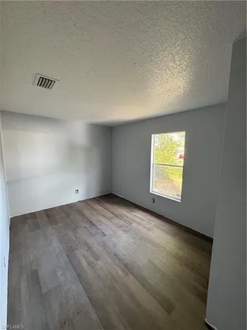 Room featuring wood-finish flooring, light gray wall paint, and a window providing natural illumination