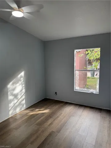 Room featuring wood-finish flooring, a ceiling fan with integrated lighting, and a window providing natural illumination
