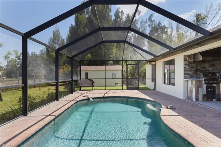 Outdoor pool featuring area for grilling, a patio, a lanai, and a grill