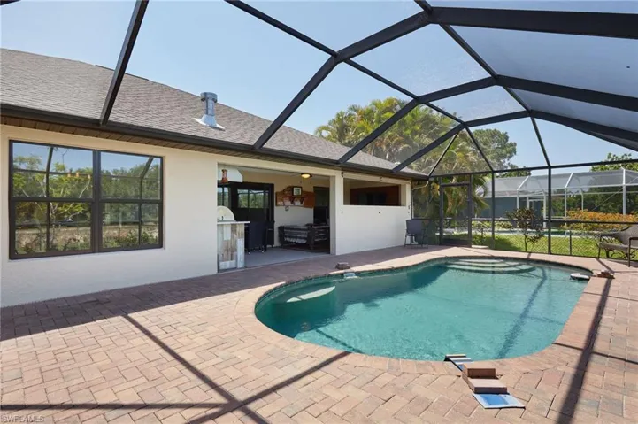 Outdoor pool with exterior kitchen, a patio area, and a lanai