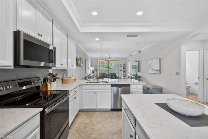 Kitchen featuring white cabinetry, stainless steel appliances, light-toned countertops, and a gray subway tile backsplash