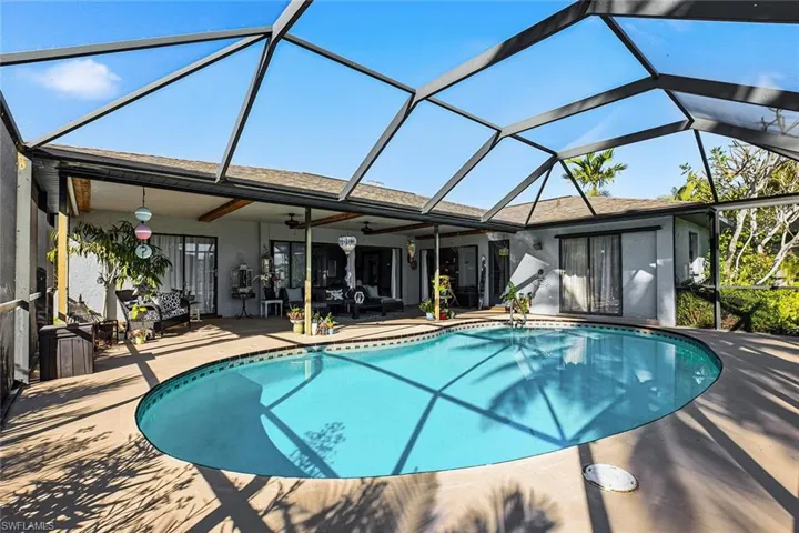 Outdoor pool with glass enclosure, a sunroom, and a patio area