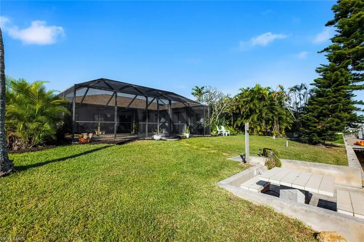 View of grassy yard featuring glass enclosure, a sunroom, and a patio