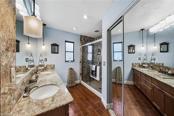 Bathroom with double vanity, wood finish floors, and a shower stall
