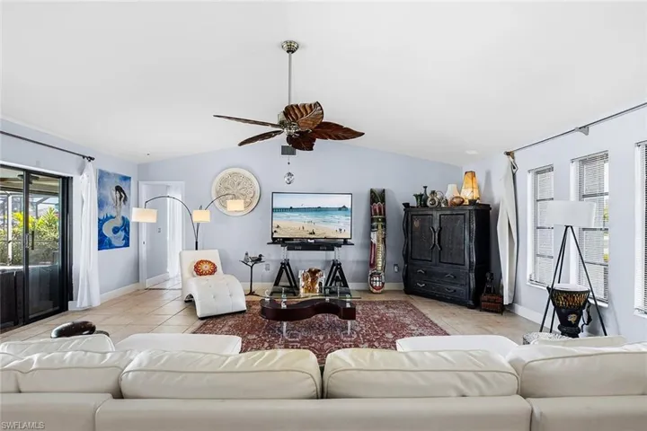 Living room with lofted ceiling, a ceiling fan, and tile patterned floors