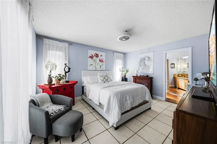 Bedroom featuring a textured ceiling, light tile patterned floors, and connected bathroom
