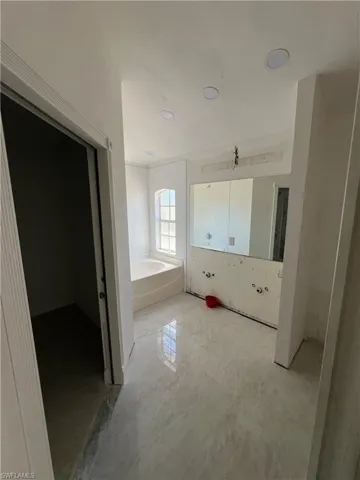 Full bathroom featuring a bath and light marble finish floors