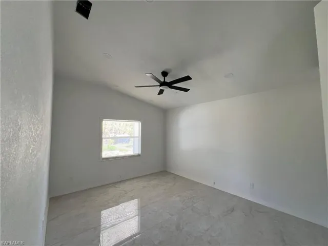 Empty room featuring vaulted ceiling and ceiling fan