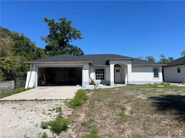 Ranch-style home featuring driveway, an attached garage, and stucco siding
