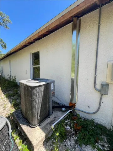 Exterior view of stucco siding and a central AC unit