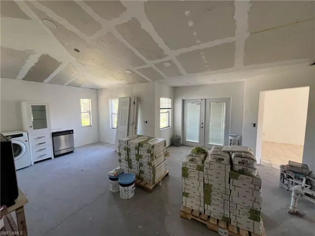 Living area featuring french doors, washer / dryer, and concrete floors