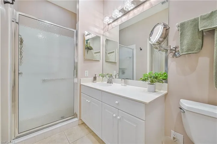 Bathroom featuring vanity, tile patterned floors, walk in shower, and toilet