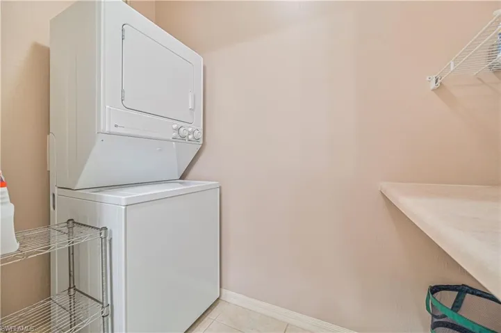 Laundry room with stacked washer / dryer and light tile patterned floors